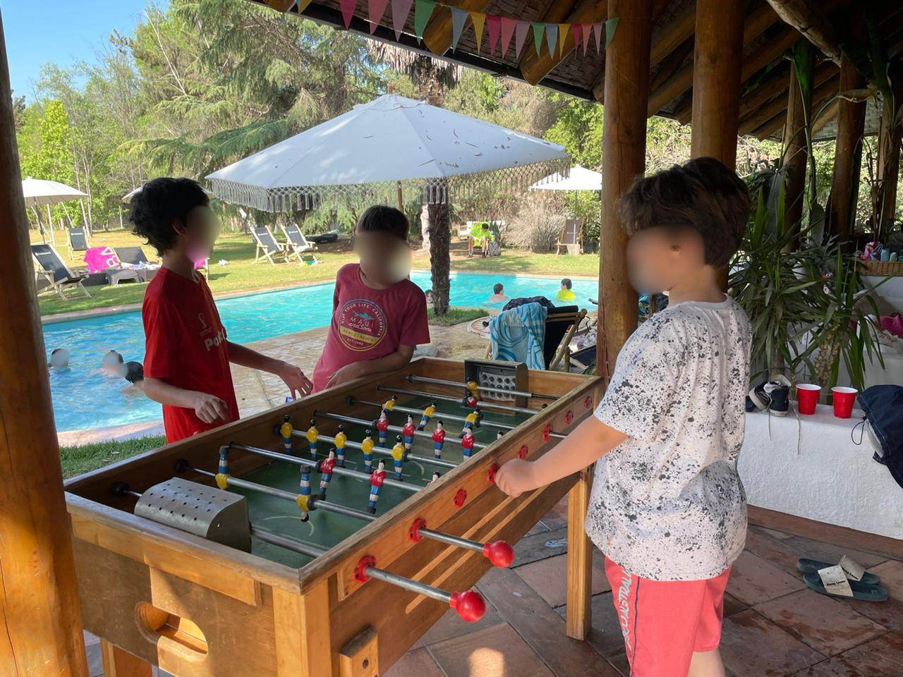 Niños jugando taca-taca junto a la piscina